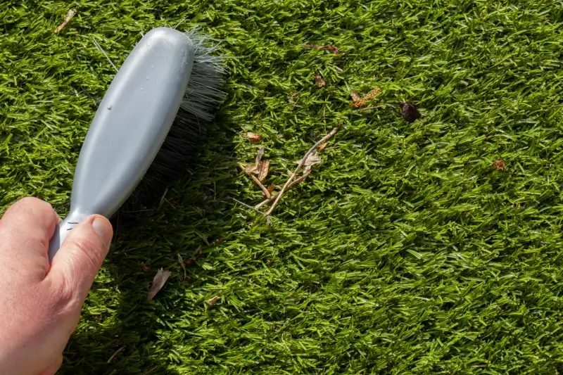 Landscaper brushing artificial turf.