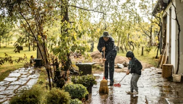 Father and son in middle of lawn that is flooding.