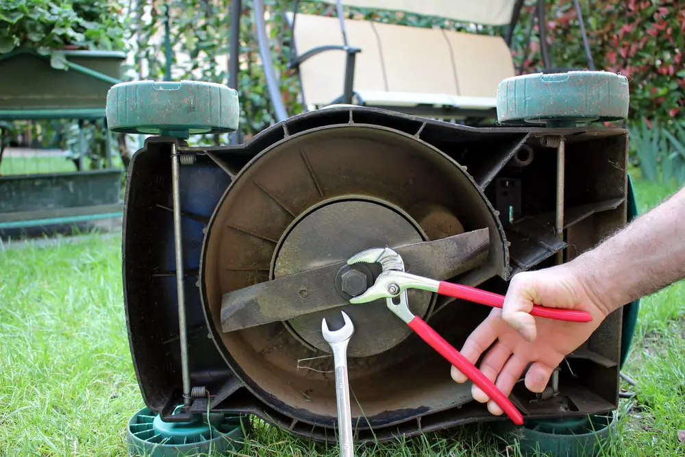 Landscaper doing maintenance on lawn mower