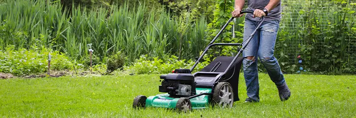 The Grounds Guys landscaper mowing a lawn