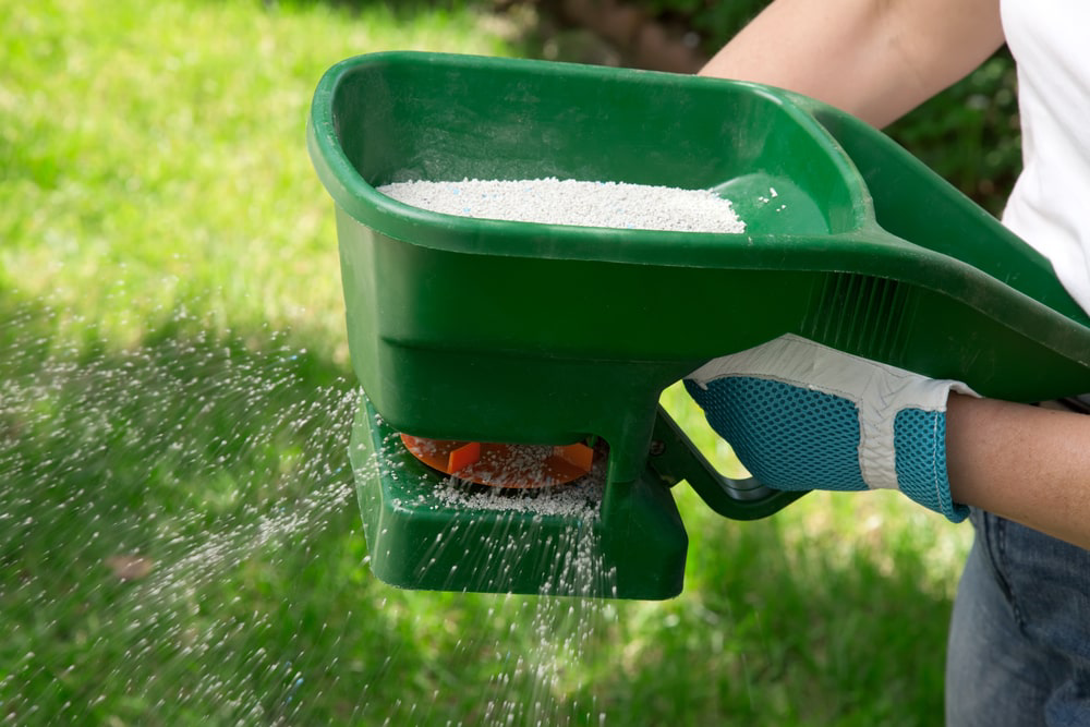 Landscaper using lawn fertilizer tool