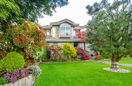 A two-story home with a lush, green landscape and lawn.