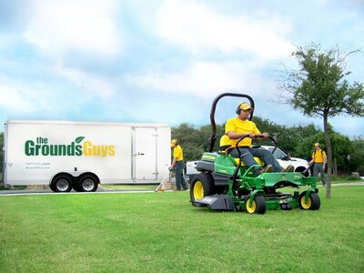 Three professional and uniformed Grounds Guys staff performing yard work services