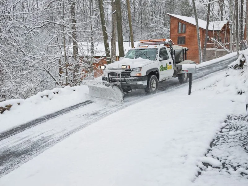 Grounds Guys truck clearing snow & ice from road.