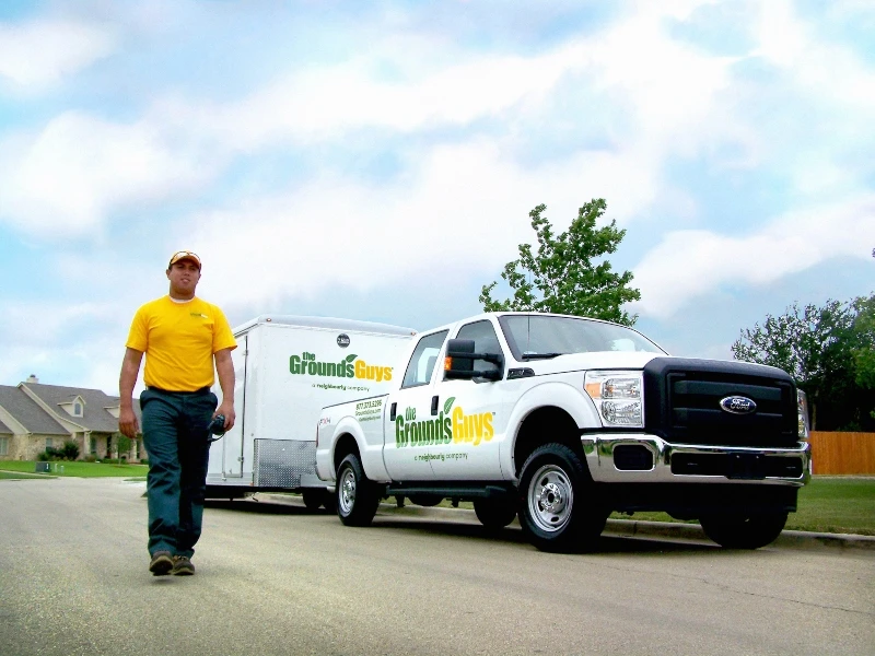 Grounds Guys landscaper walking to help with a drainage installation.