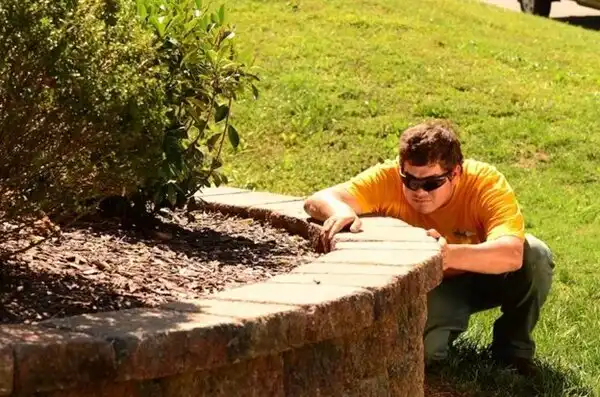 Grounds Guys landscaper installing a paver during a hardscape installation project.