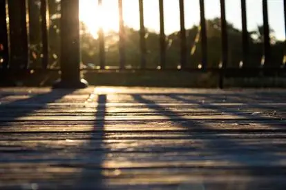 A rising sun shining on a wood deck.