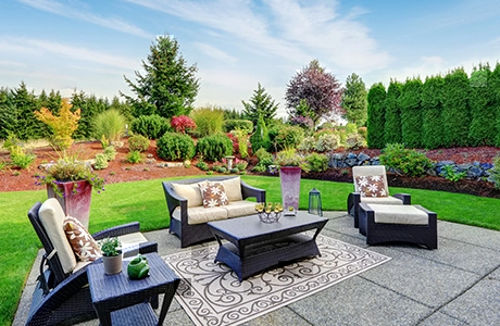 Beautiful backyard landscape with outdoor furniture on a stone patio.