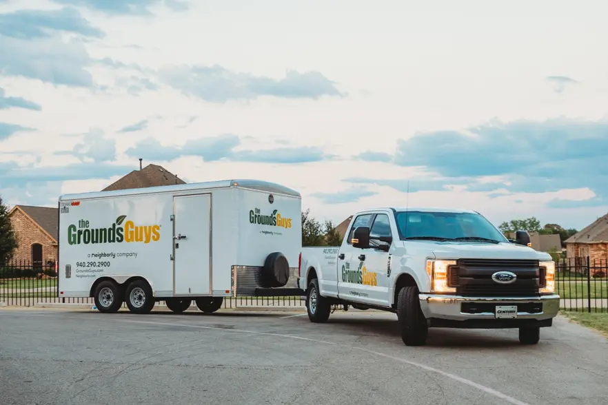 The Grounds Guys branded pickup truck with branded trailer attached.