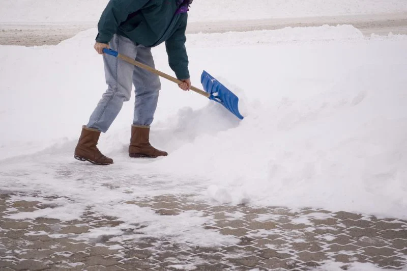 Grounds Guys landscaper clearing snow from driveway.