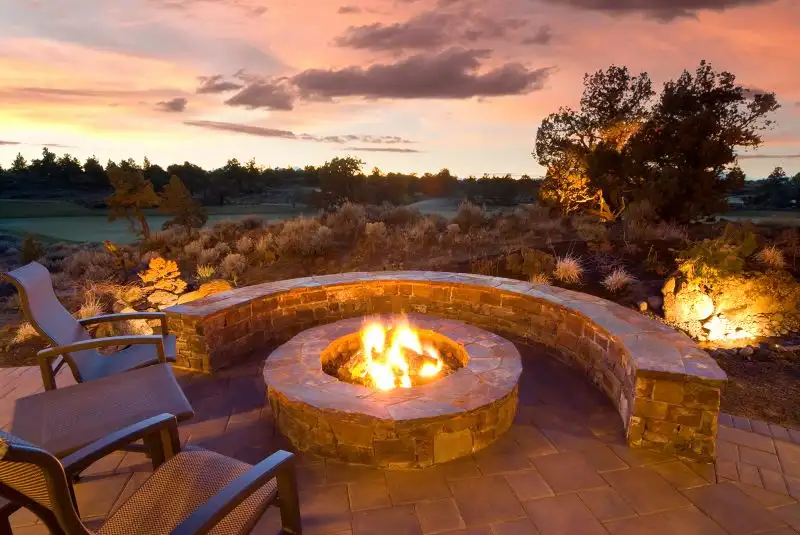 Lit stonework fire pit with built-in wrap-around bench.