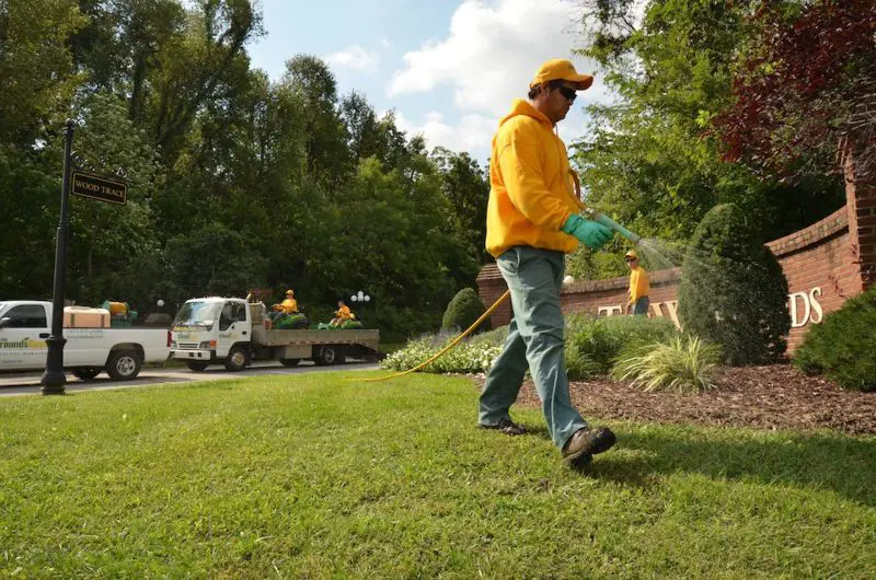 Grounds guys landscaper spraying lawn for commercial fertilization and weed services